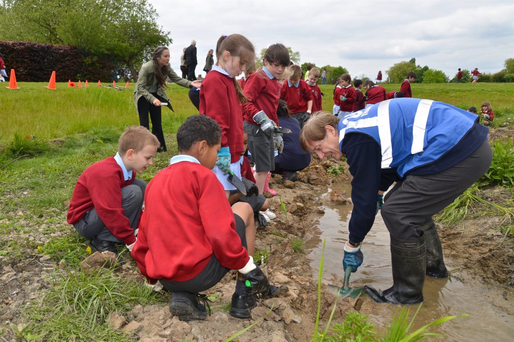 Volunteers and school children digging in a stream