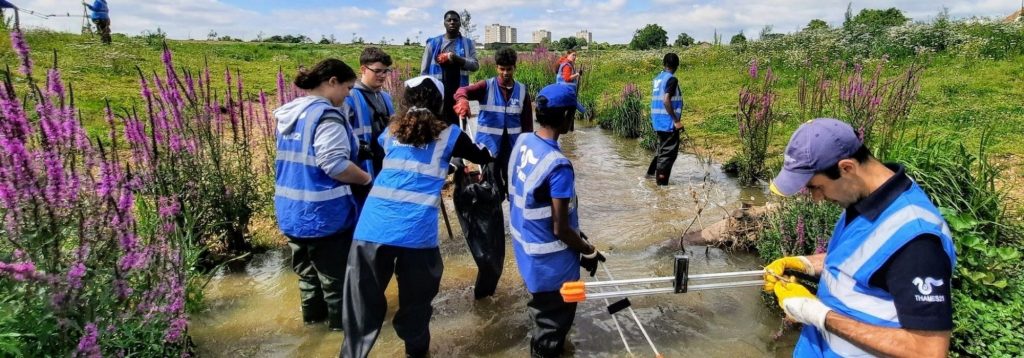 Volunteers in Thames21 high vis jackets working in a small waterway