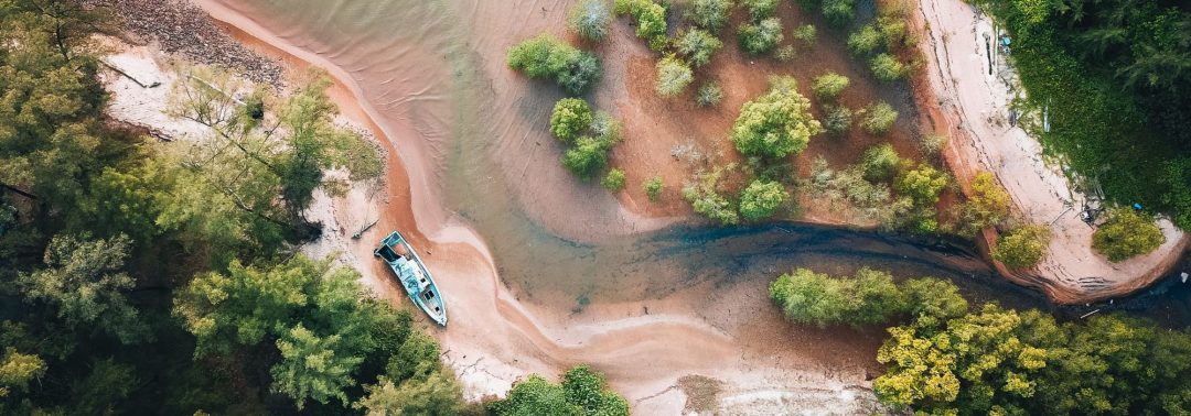 Landscape image of a boat and river flowing to the sea surrounded by trees